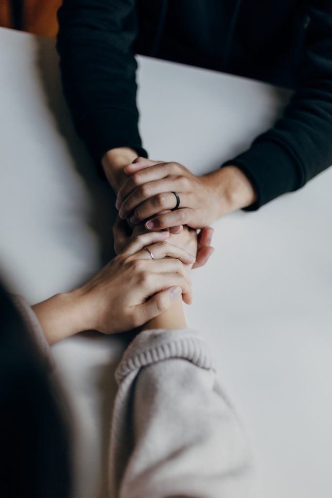 counselling session with counsellor and person holding hands discussing suicide prevention.