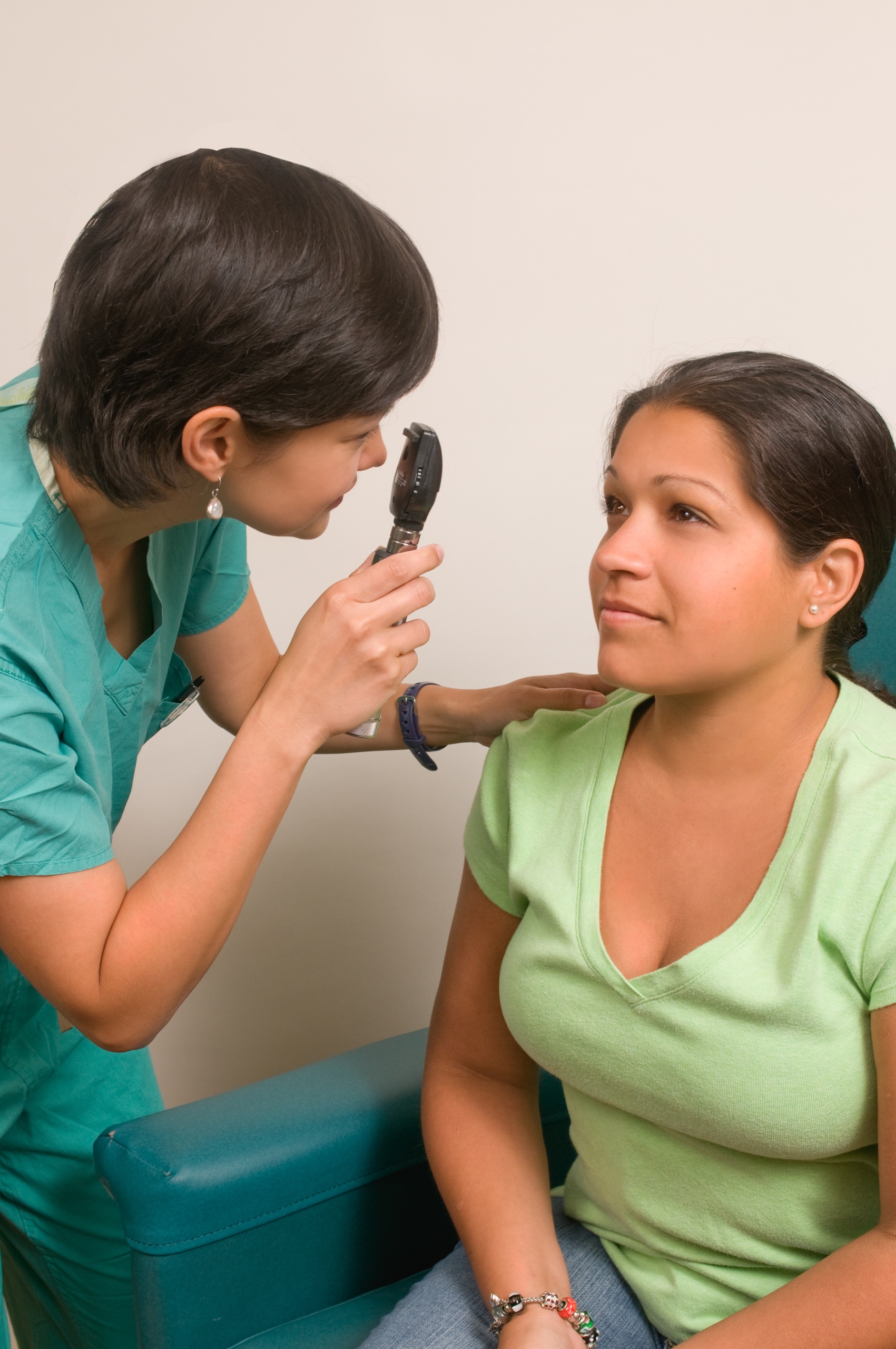 eye doctor checking a woman's eye through her benefits coverage