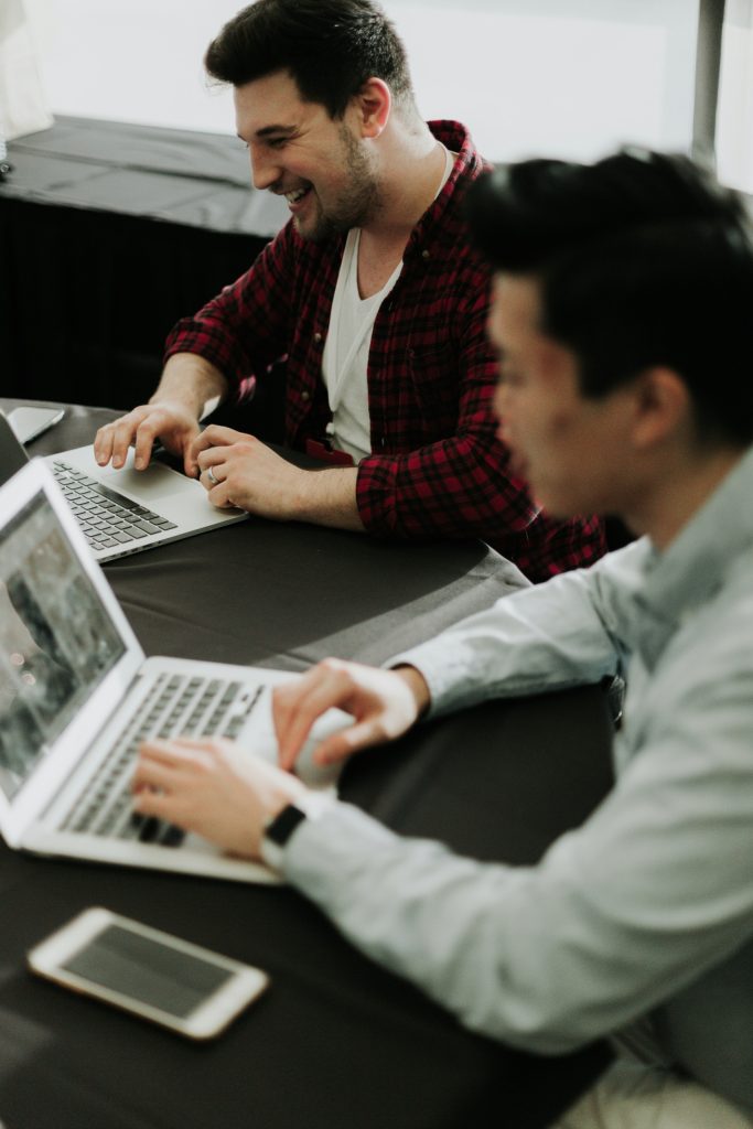 two happy employees working on computers that understand that employee mental health matters.