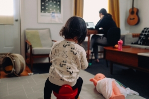 A woman with flexible work arrangements working from home while looking after their child.